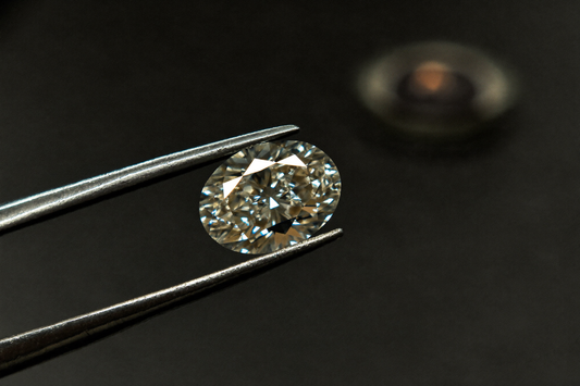 Ovaler Labordiamant in einer Pinzette vor dunklem Hintergrund