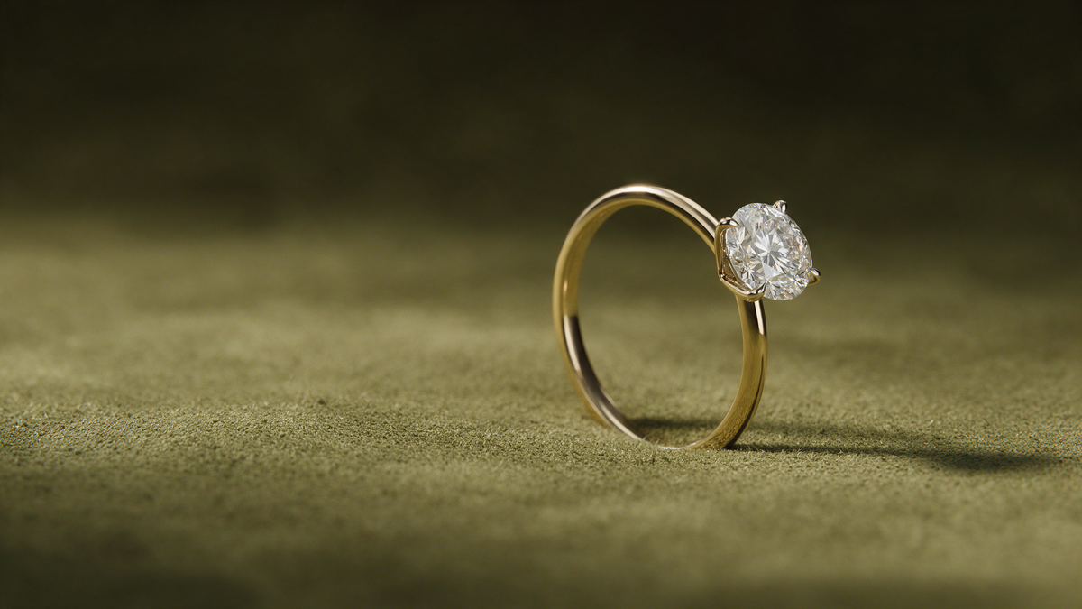 Verlobungsring aus Gelbgold mit rundem Labordiamanten auf olivfarbenem Wildleder